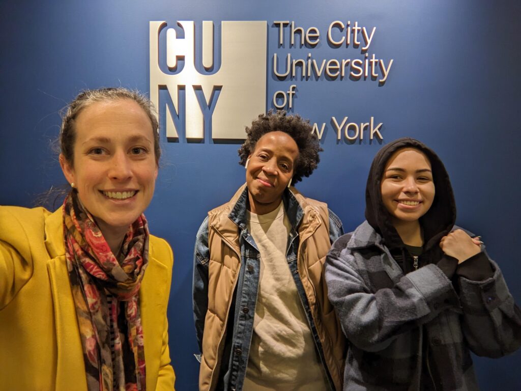 Christina Katopodis stands with Fall 2022 Student Advisory Board Members Tahisha Fields and Holliday Senquiz in front of a CUNY logo at the 42nd St Central Office